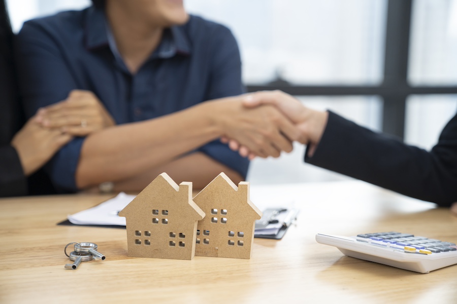 real estate agent and customers shaking hands together celebrating finished contract